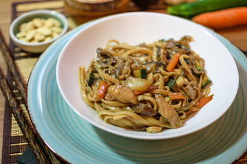 Rice noodles served with vegetables and meat in white bowl.