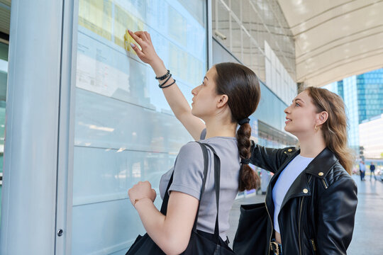 Two young females reading the transport timetable on the scoreboard