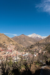 Fototapeta na wymiar A town sits on the skirts of the mountains of the Ourika Valley in the High Atlas of Morocco