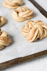 Swedish cinnamon buns dough on a parchment lined baking pan, unbaked cinnamon twists, process of making Kanelbullar