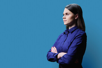 Profile view, portrait of serious young woman in on blue background, copy space