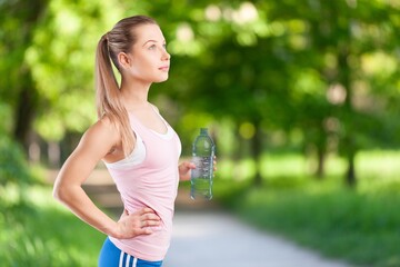 Happy slim young woman drinking clean water after workout