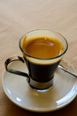 Small glass cup of black arabica coffee served in cafe, close up