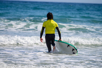 Young surfers train on Playa de Palombina Las Camaras in Celorio, Green coast of Asturias, North Spain with sandy beaches, cliffs, hidden caves, green fields and mountains