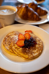 Breakfast with homemade American pancakes served with strawberry jam and fresh ripe strawberries and croissants