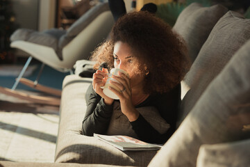 Reading magazine, woman, thoughtful pause, hot drink sip, mug, h
