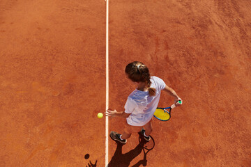 Top view of a professional female tennis player serves the tennis ball on the court with precision and power
