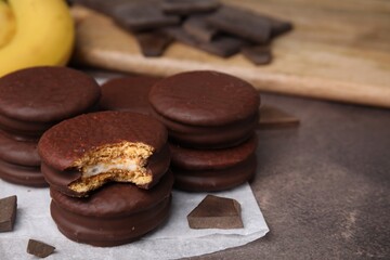 Tasty banana choco pies and pieces of chocolate on textured table, closeup. Space for text