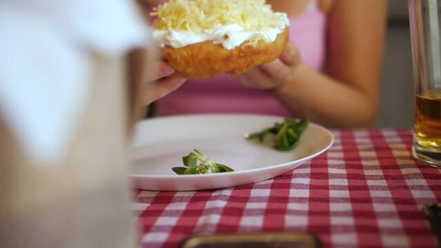 Woman Eating A Cheesy And Creamy Langos Dish In Hungarian Restaurant. - closeup