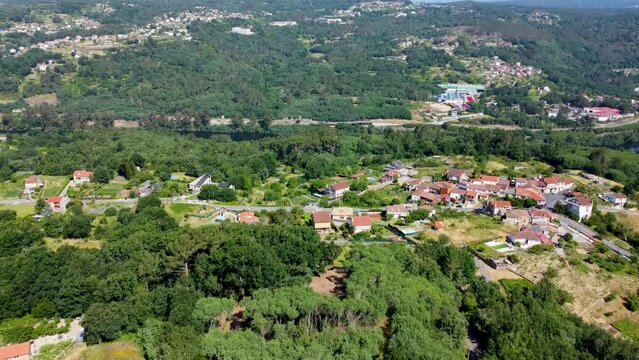 Aerial rising reveal of mi&ntilde;o river forest and countryside town of velle in spain