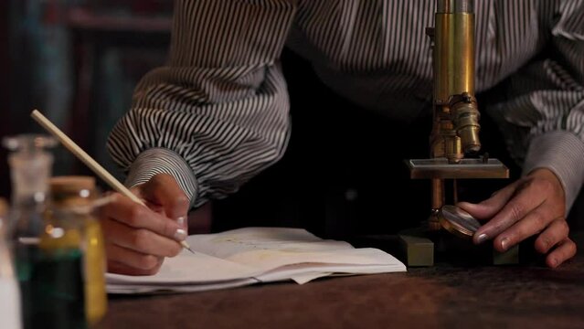 closeup victorian scientist making notes from microscope