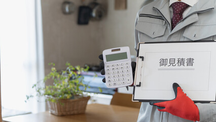リビング・キッチンで電卓と見積書を持つ作業服の男性