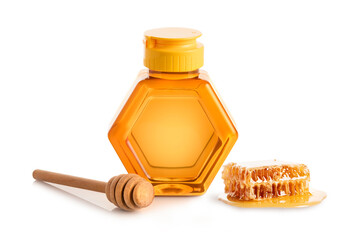 Bottle of honey with wooden dipper and honey comb on white
