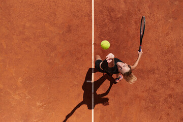 Top view of a professional female tennis player serves the tennis ball on the court with precision and power