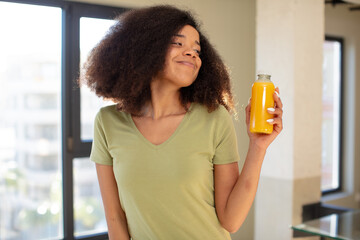 pretty afro black woman smiling and looking with a happy confident expression. orange juice concept