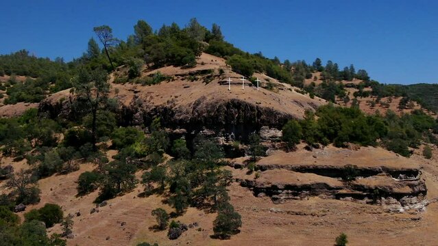Aerial cinematic drone calvary cross Richard Springs YWAM Chico California Upper Bidwell Park butte cave creek canyon three cross on hillside crucifixion place of skull mid day sunny circling motion