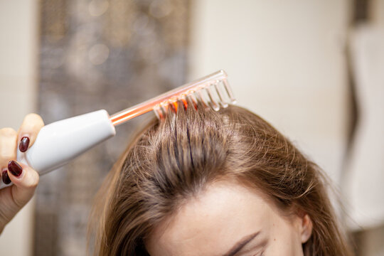Woman uses darsonval for massage head's skin. Receiving electric darsonval facial massage procedure. Face Beauty Treatment. Darsonval Therapy Using High Frequency D'Arsonval, Skin Care Device.