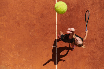 Top view of a professional female tennis player serves the tennis ball on the court with precision...