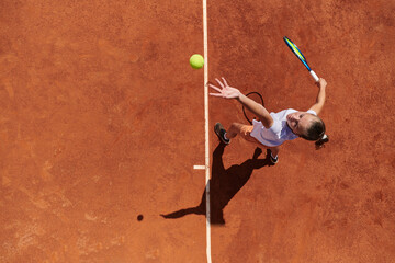 Top view of a professional female tennis player serves the tennis ball on the court with precision...