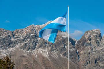 Light blue and white Argentinian flag waving with a mountain and blue sky as a background in patagonia argentina