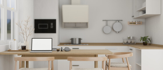 A laptop mockup on a wooden dining table in modern contemporary white kitchen