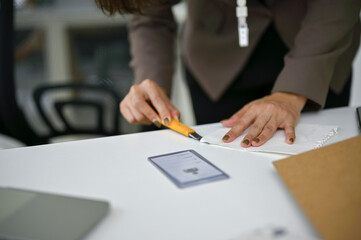 Fototapeta premium Close-up image of a businesswoman using a cutter to cut a paper at her desk