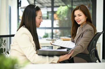 Focused Asian businesswoman sharing her ideas and discussing work with her colleague