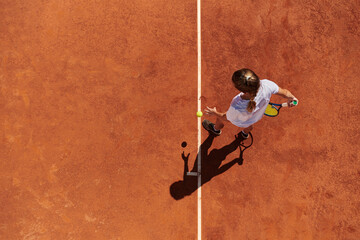 Top view of a professional female tennis player serves the tennis ball on the court with precision...