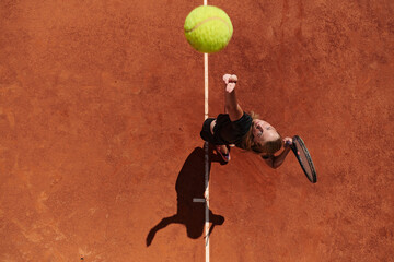 Top view of a professional female tennis player serves the tennis ball on the court with precision...