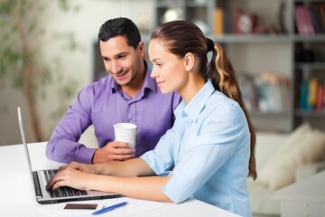 Two cheerful office workers work with laptop,