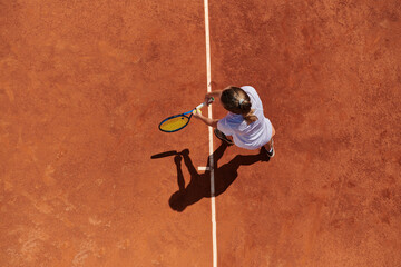 Top view of a professional female tennis player serves the tennis ball on the court with precision and power