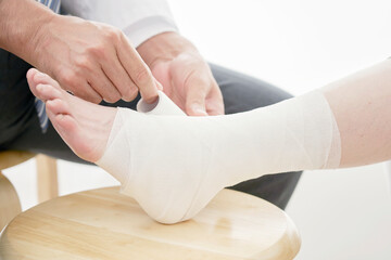 足首に包帯を巻く医者　顔無し