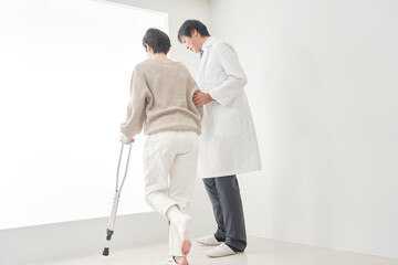 Fototapeta na wymiar 医者と松葉杖を使って歩く中年女性