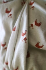 the fabric texture of a baby's dress is light green with a deer pattern