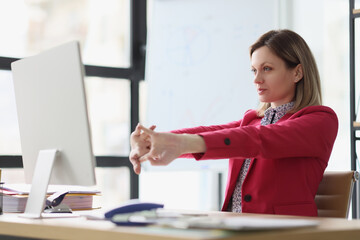 Lady manager stretches arms before starting work on computer