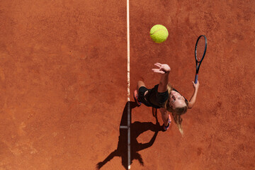 Top view of a professional female tennis player serves the tennis ball on the court with precision and power - obrazy, fototapety, plakaty