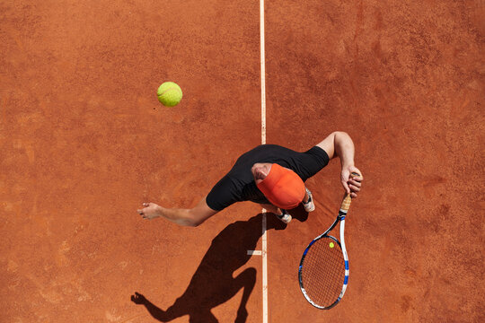 Top view of a professional tennis player serves the tennis ball on the court with precision and power