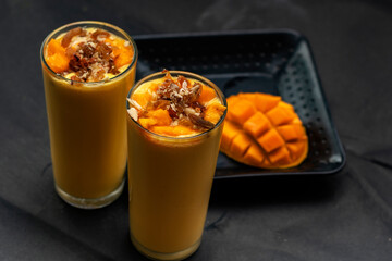 Mango lassi or mango yogurt smoothie garnished with mango slice a popular drink in India.