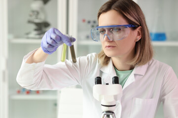 Fototapeta premium Woman holds test tubes with yellow and brown liquids samples