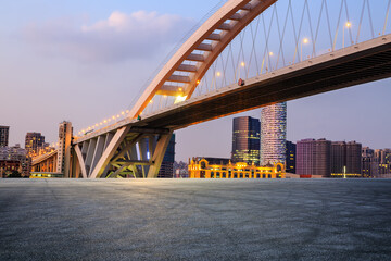 Asphalt road and bridge with urban architecture at sunset