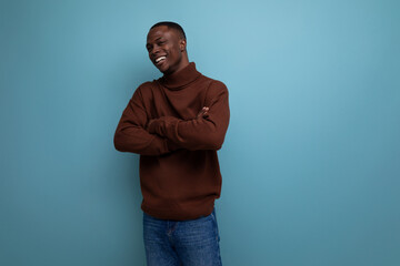 dark-skinned 25 year old guy with a short haircut in a brown sweater laughs on a studio background...