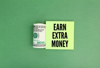 a roll of paper money and colored paper with the word earn extra money. the concept of earning...