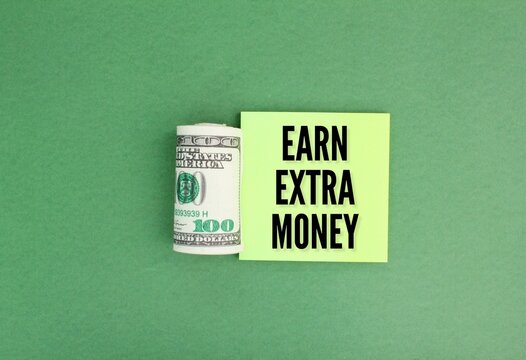a roll of paper money and colored paper with the word earn extra money. the concept of earning extra money. the concept of extra money. Concept of financial planning Make more extra money 