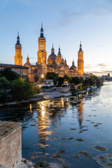 Naklejka premium Zaragoza, Spain - May 01, 2023: ebro river, in front of the Basilica del Pilar, with very low water level due to drought and climate change in Zaragoza, Spain