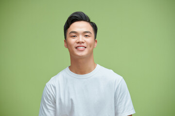 Close up portrait of smiling handsome man in white t-shirt looking at camera, isolated on green...
