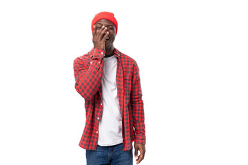 successful pensive 30s black american man dressed in red shirt and cap on white studio background with copy space