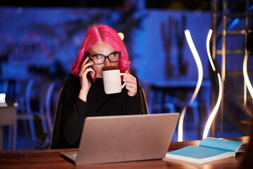 Businesswoman answering late phone call from another country and drinking coffee