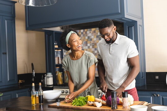 Happy African American Couple Cutting Vegetables, Preparing Meal Together In Kitchen