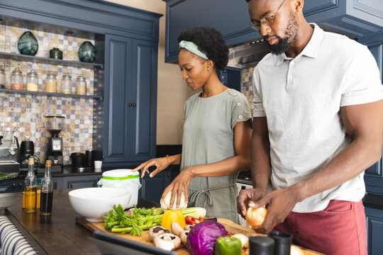 Happy african american couple preparing vegetables for meal together in kitchen