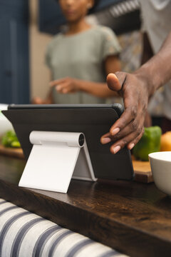 African american couple preparing meal together using tablet in kitchen, copy space
